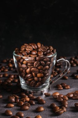 Siyah arka planda şeffaf bir fincanda kahve çekirdekleri. Doğal ışık