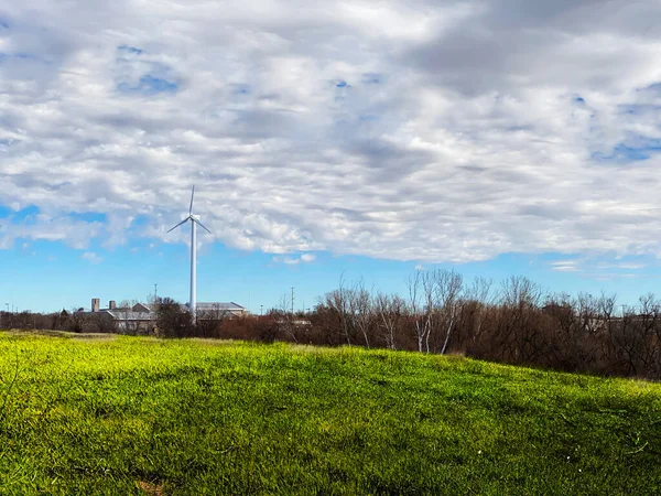 a wind turbine factory energy supply power plant green field blue sky clouds landscape