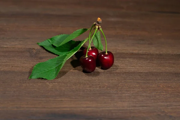 成熟的红樱桃 绿色的叶子 木制的桌子上 — 图库照片