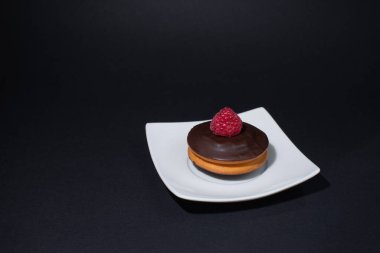 Lezzetli peynirli kek, beyaz tabakta ahududu ve koyu beton bir arka plan..