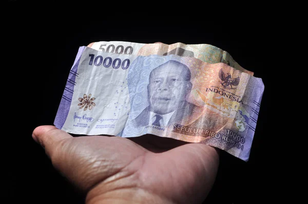 stock image Indonesian rupiah banknotes in hand black background