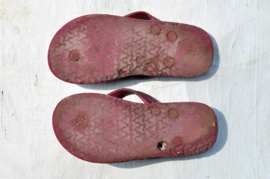 Beyaz arka planda eskimiş ve çirkin parmak arası terlikler