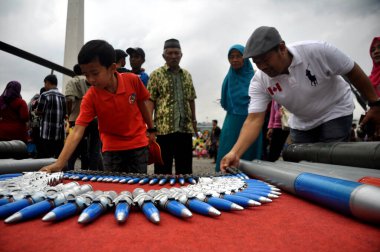 Jakarta, Endonezya - 13 Aralık 2014: Cakarta sakinleri, Monas, Jakarta - Endonezya 'daki TNI savaş gereçleri sergisinde yer alan savaş uçaklarının mermilerine bakıyorlar