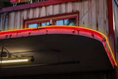 Eski, iyi korunmuş bir benzin istasyonu, turuncu kollarla aydınlatılmış..