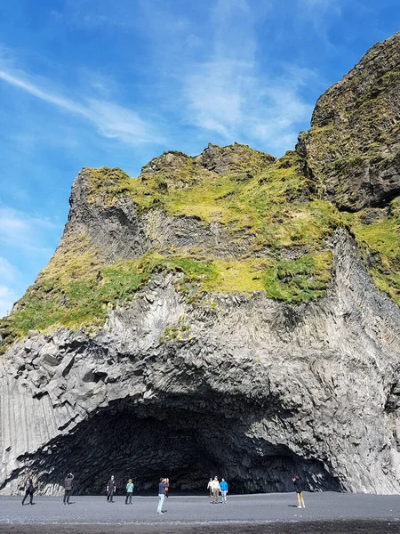 People outside a cave at Reynisfjara beach in Iceland