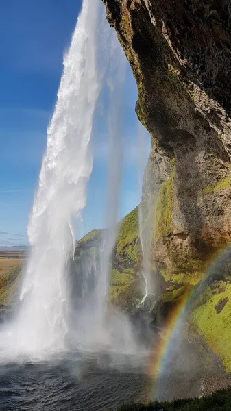 Seljalandsfoss waterfall in Iceland with rainbow on a sunny late summer day