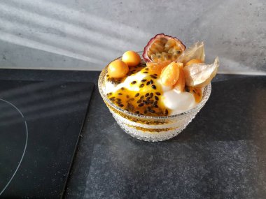 Self-made dessert in a glass bowl with passion fruit and ground cherries