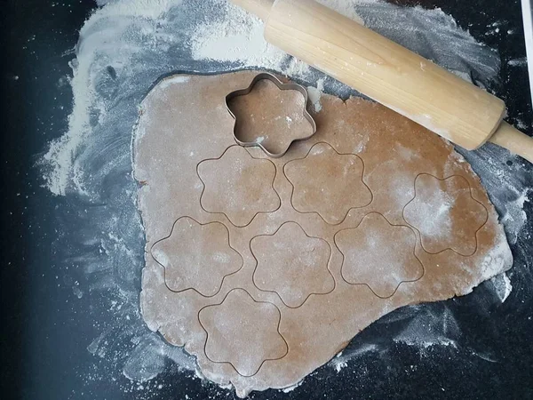 Gingerbread dough, flour, molds and a rolling bin on kitchen counter