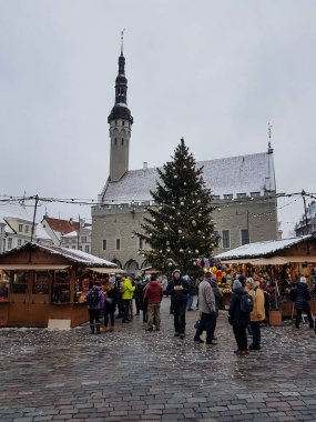Old city hall, people, Christmas market stalls and a Christmas tree in Tallinn, Estonia