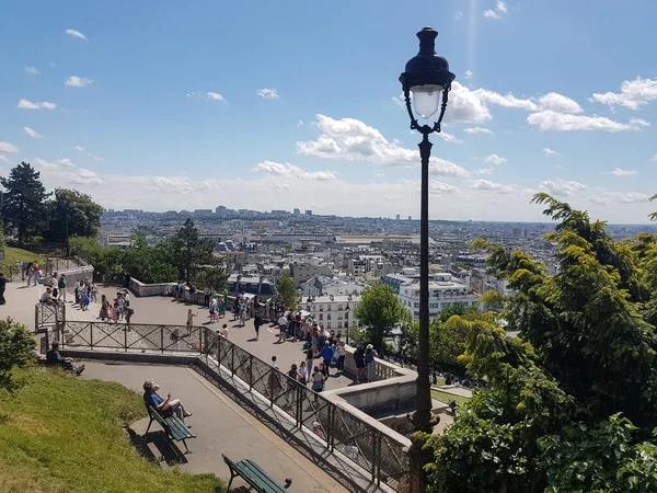 People admiring the view over Paris rooftops in Montmartre on a sunny summer day
