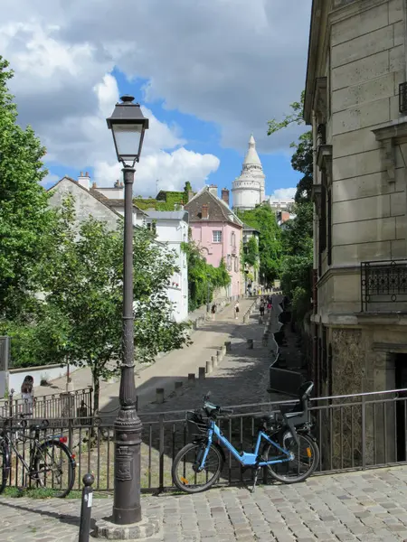 Street view in Montmartre, Paris with a lamppost, bicycles, old houses and part of the Sacre-Coeur Basilica