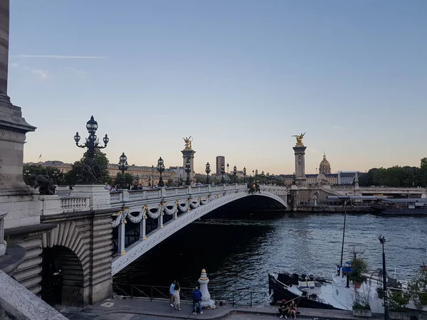Lampposts, sculptures, Seine river and Pont Alexandre III bridge in Paris, France 