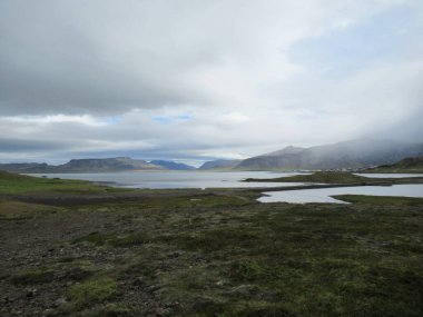 Grass, sea, mountains and clouds in Iceland