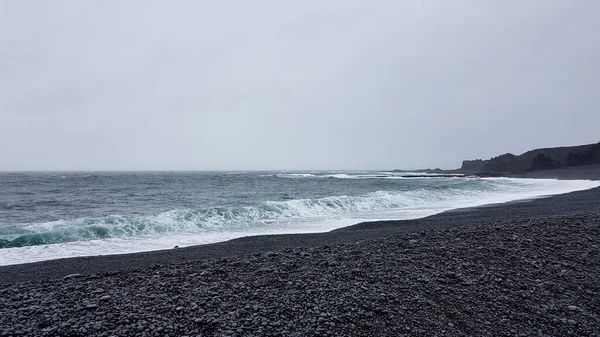 Strong ocean waves hitting black sand beach at Djupalonssandur beach in Iceland