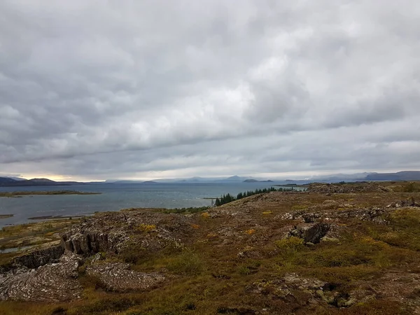 Lake, island and rocks with mountains on the background at Thingvellir National Park in Iceland