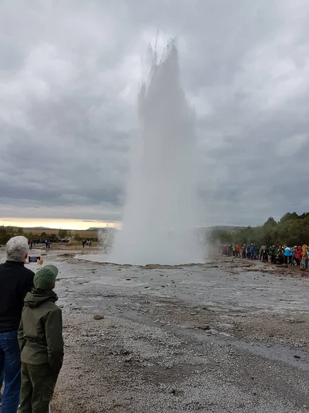 Tourists watching the geyser Strokkur erupt in Iceland