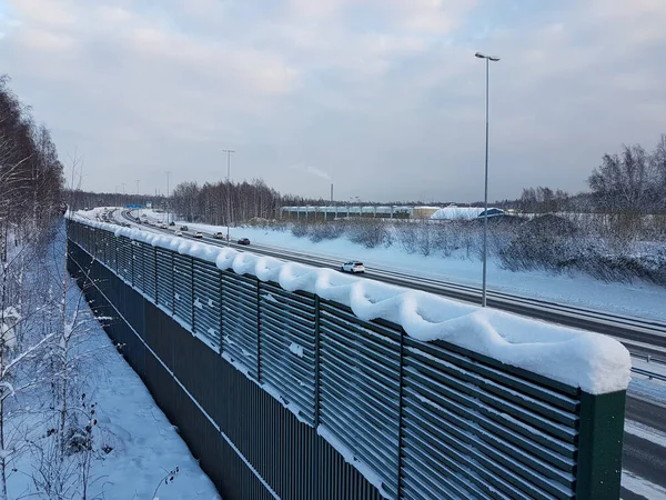 Nature-made snow art on top of a noise cancelling fence next to a highway at winter