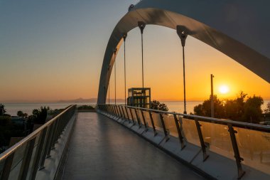 Gün batımında şehirde işlek bir yol üzerinde yaya köprüsü