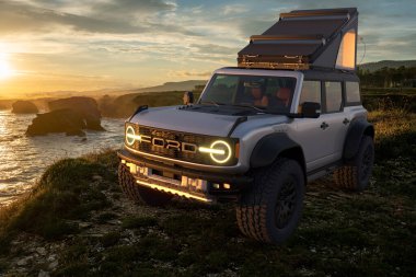  Ford Bronco Raptor vahşi arazide, keşif ekipmanları ve bir çatı çadırıyla donatılmış.