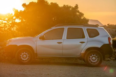 Dacia Duster SUV arka planda dağlar olan çakıllı bir otoparkta..