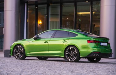 Audi S-5 modern bir apartmanın girişine park etmiş.