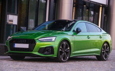 Audi S-5 modern bir apartmanın girişine park etmiş.