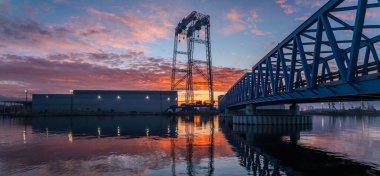 Endüstriyel peyzaj-kiriş köprüsü muhteşem gündoğumu sırasında deniz endüstrisi üretim binalarına yol açıyor
