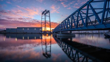 Endüstriyel peyzaj-kiriş köprüsü muhteşem gündoğumu sırasında deniz endüstrisi üretim binalarına yol açıyor