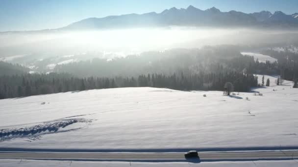 冬の雪と乗用車 空中視界で覆われた山道 エピック 雪の白い冬 雪が山の範囲を捉えました 壮大なアルペンビューと車の運転による道 ウィンターロードトリップ — ストック動画