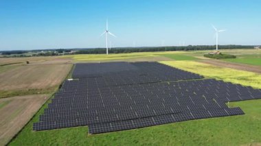 Güneş çiftliği ve rüzgar türbinleri hava manzaralı. Güneş enerjisi panelleri, fotovoltaik ve rüzgar çiftliği. Ekin yakınında güneş enerjisi santrali. Sürdürülebilir kaynaklar ve alternatif elektrik kavramı