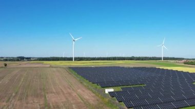 Güneş çiftliği ve rüzgar türbinleri hava manzaralı. Güneş enerjisi panelleri, fotovoltaik ve rüzgar çiftliği. Ekin yakınında güneş enerjisi santrali. Sürdürülebilir kaynaklar ve alternatif elektrik kavramı
