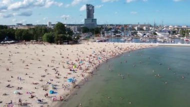 Modern bir sahil kenti olan Gdynia 'da kumsal, hava manzaralı. Yat limanı ve yat limanı yakınlarındaki kalabalık sahili çekiyoruz. Güneşli bir yaz gününde Baltık Denizi kenarında güneşlenmek.
