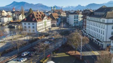 Time Lapse, traffic in the European town on sunny winter day. Swiss town with mountains on the background. River Reuss. Lucerne, Switzerland.