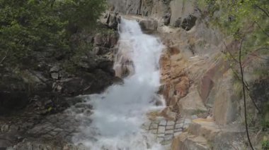 Dağlarda şelale. Wassen yakınlarındaki yüksek dağlardaki kayalardan su düşüyor. Rohrbach, Reuss Vadisi, Canton Uri, İsviçre.