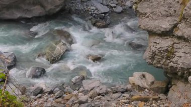 Soğuk ve hızlı dağ nehri kayaların etrafından geçiyor ve beyaz köpük girdapları yapıyor. Linth Nehri, Linthal, Glarus Kantonu, İsviçre