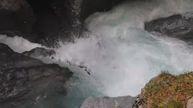 Soğuk ve hızlı dağ nehri kayaların etrafından geçiyor ve beyaz köpük girdapları yapıyor. Linth Nehri, Linthal, Glarus Kantonu, İsviçre