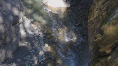 Soğuk ve hızlı dağ nehri kayaların etrafından geçiyor ve beyaz köpük girdapları yapıyor. Hinterrhein Nehri, Andeer, İsviçre Graubnden Kantonu