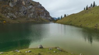 Zaman atlaması, dağlarla çevrili bir göl manzarası. Dağların tepesinde sakin ve huzurlu bir göl. Bannalp Gölü, Bannalpsee, Bannalp, Nidwalden Kantonu, İsviçre.