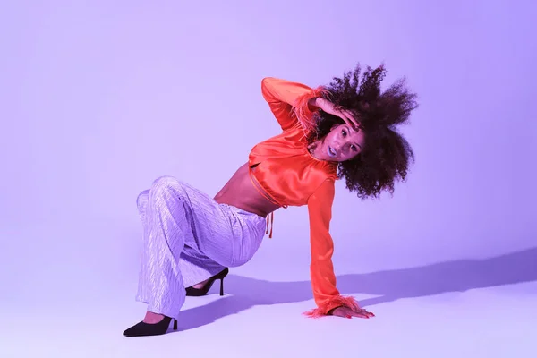 stock image Latin girl with curly hair and colorful clothes smiling and looking at camera touching her hair while dancing