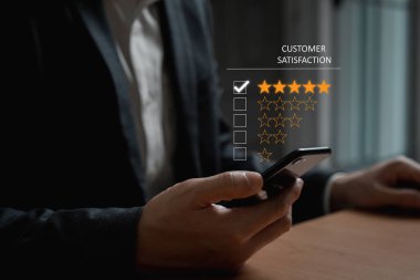 Seçici olarak iş adamının parmağına odaklanırken, işaret parmağı da gülümseyen beş yıldızlı mükemmel müşteri hizmetleri hakkında geri bildirim seçecek. Fütürist simgeyle servis değerlendirme kavramı.