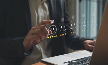 Seçici olarak iş adamının parmağına odaklanırken, işaret parmağı da gülümseyen beş yıldızlı mükemmel müşteri hizmetleri hakkında geri bildirim seçecek. Fütürist simgeyle servis değerlendirme kavramı.