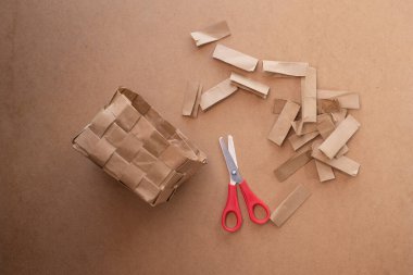 Geri dönüştürülmüş kağıt torbadan yapılmış sepet, DIY, adım adım talimatlar, makasla örülmüş ve kesilmiş kağıt şeritler, üst görünüm