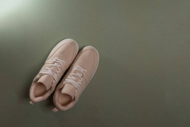 Bej tekstil dantelli spor ayakkabılar, üst manzara, yeşil arka planda kadın ayakkabıları.