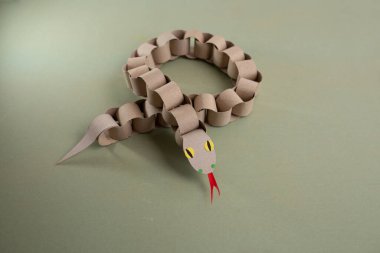 Tuvalet kağıdı rulolarından bir yılan, geri dönüşüm kartonu, DIY, özel ders, çocuklar için eğitim sanatı, kağıt zincirli piton oyuncağı