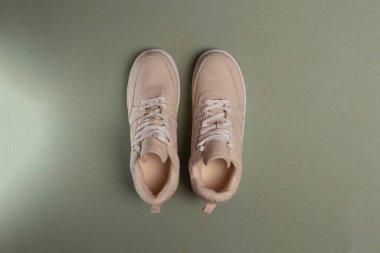 Bej tekstil dantelli spor ayakkabılar, üst manzara, yeşil arka planda kadın ayakkabıları.