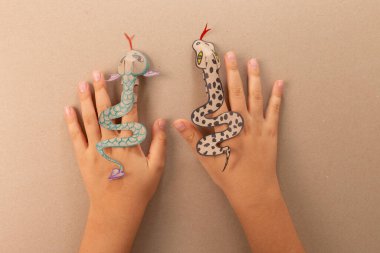 Kağıt yılanlı hayvanların el sanatları, bir çocuk çizimi, sevimli bir oyuncak, geri dönüşümlü kağıttan yapılmış bir parmak ejderhası, DIY, özel ders, eğitim sanatı ve çocuklar için el işi.