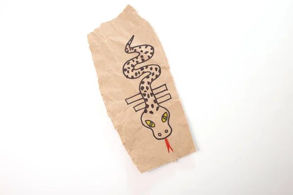 childrens drawing of a snake or dragon craft made out of recycled paper, DIY, tutorial, educational art and craft for kids, top view, a close up of a persons hand holding a toy snake,