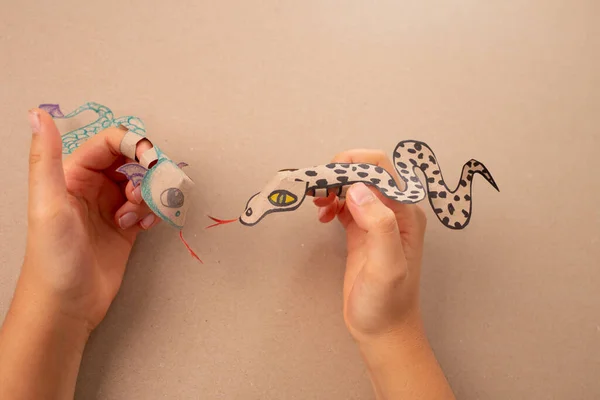 Geri dönüşümlü kağıttan yapılmış bir parmak yılanı veya ejderha zanaatı, DIY, özel eğitim sanatı ve çocuklar için el işi, üst görünüm, bir insan kağıttan bir yılan yapıyor, ayrıntılı çizim, işleme sanatı, kuklalar, 