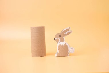 Çocuk ve anaokulu, spor salonu, özel ders, bahar oyuncağı, geri dönüşüm sanatı, sarı turuncu yüzey üzerinde oturan kahverengi ve beyaz tavşan, kağıt kesim, 