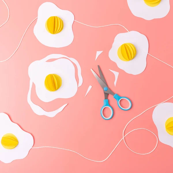 fried eggs paper craft on a pink background, Easter decoration concept, art project for kids, how to make an egg garland, DIY, easy origami, top view